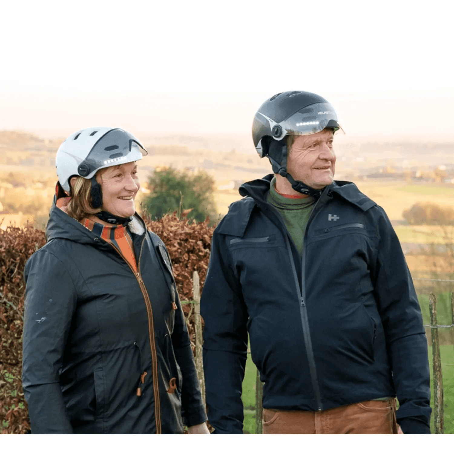 Seniorenpaar mit H+ E-Bike Helm in Schwarz und Weiss, mit transparentem und abgedunkeltem Visier.